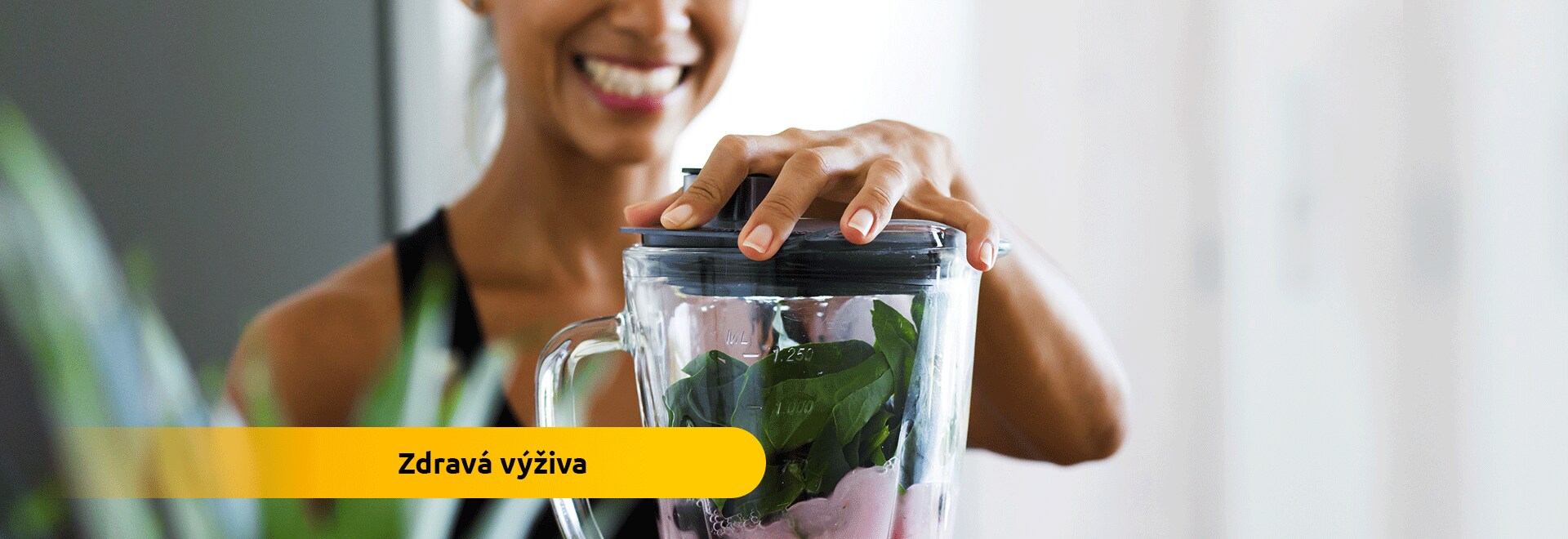 Mladá žena mixuje povzbudzujúci nápoj smoothie